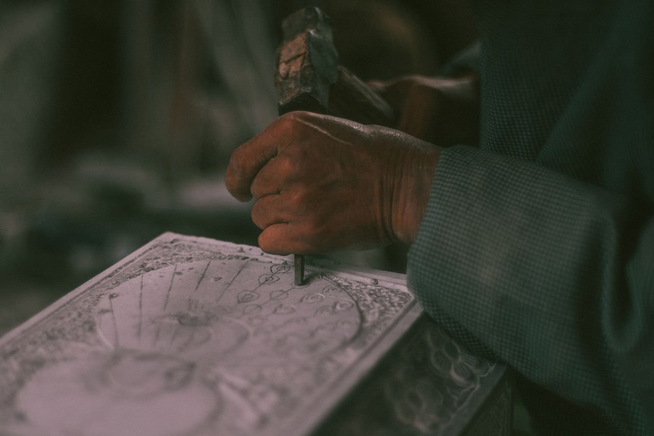 Close-up of a skilled artisan creating detailed art using hand tools on paper.