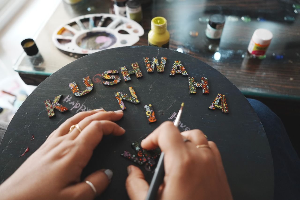Close-up of colorful handcrafted letters being painted on a round surface. Creative art scene.