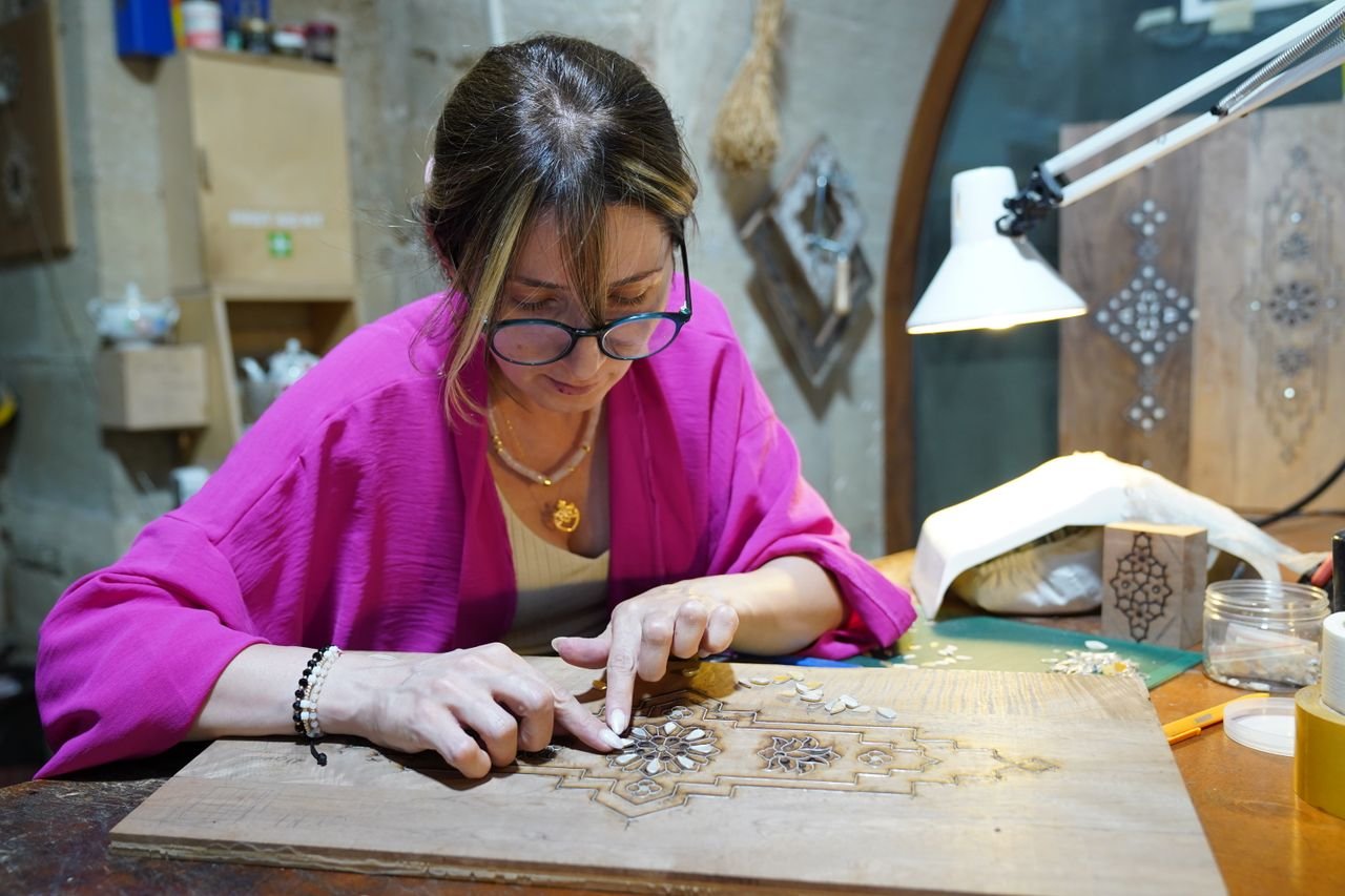 Artisan focused on crafting an intricate wood inlay design in a workshop.