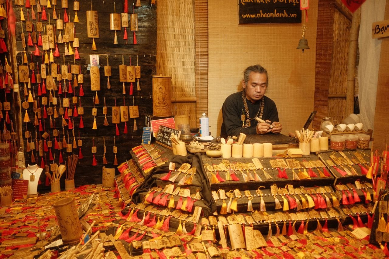Skilled artisan creating detailed bamboo crafts in a vibrant market setting.