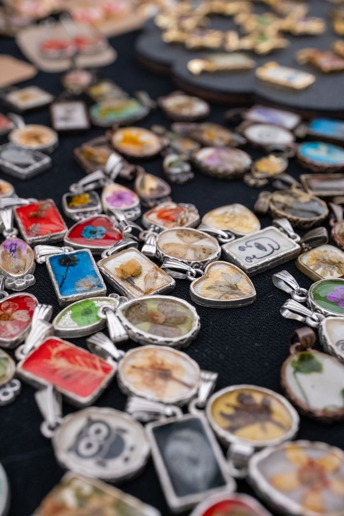 Vibrant collection of handmade pendants with floral and artistic designs displayed on a market table in Istanbul.
