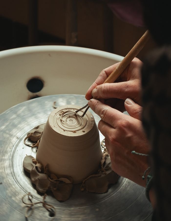 Artisan shaping a clay mug on a pottery wheel, showcasing detailed craftsmanship.